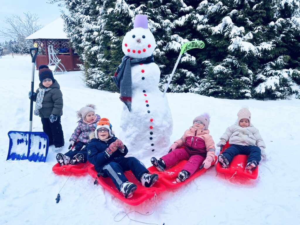 Dzieci na sankach przy bałwanku